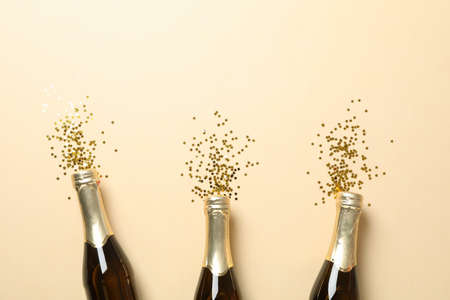 Champagne bottles and glitter on beige background, space for textの写真素材