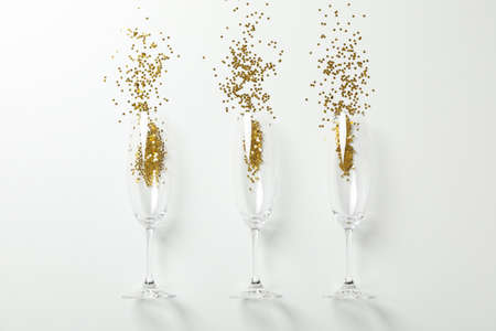 Champagne glasses with glitter on white background, space for text