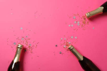 Champagne bottles and glitter on pink background, space for textの写真素材
