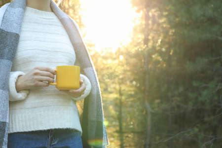 Woman hold yellow cup in forest, space for text