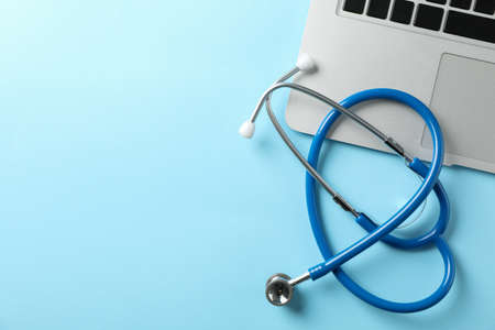 Stethoscope and laptop on blue background, space for textの写真素材