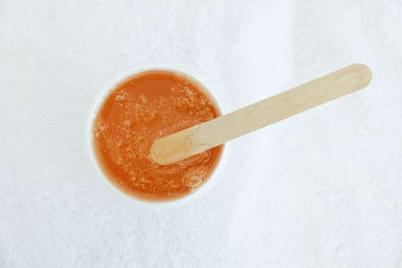 Liquid yellow paste for shugaring on white background. Depilation and body care