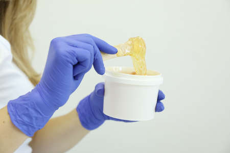 Young woman holding liquid yellow paste for shugaring on white background, copy spaceの写真素材