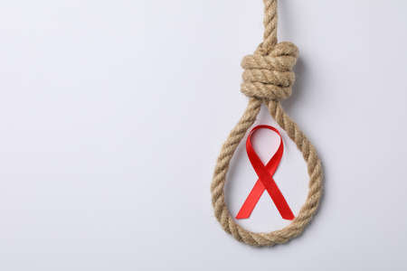 Awareness red ribbon and suicide rope on white background, copy spaceの写真素材