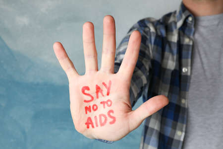 Male hand with inscription Say no to AIDS on blue background, space for text