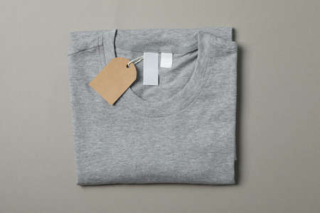 Folded blank gray t-shirt with tag on gray background, space for textの写真素材