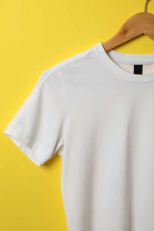 Hanger with blank white t-shirt on yellow background, space for textの写真素材