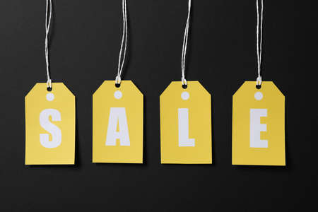 Inscription Sale on price tags on black background. Black Friday concept