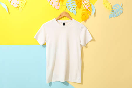 Hanger with blank white t-shirt on multicolored background, space for text