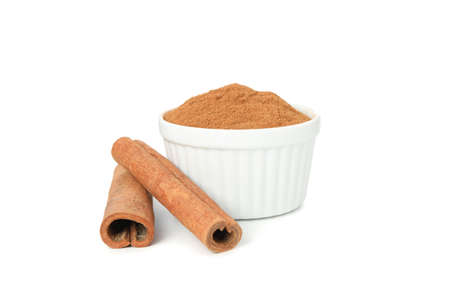 Cinnamon sticks and sauceboat with powder isolated on white backgroundの写真素材