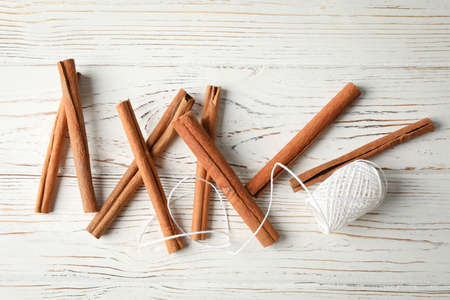 Composition with cinnamon sticks and rope on wooden background, space for text