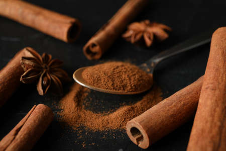 Cinnamon sticks, anise and spoon on black background, space for textの写真素材