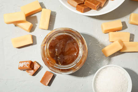 Glass jar with salted caramel and candies on grey background, top viewの写真素材