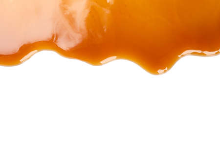 Flowing caramel sauce isolated on white background, close upの写真素材