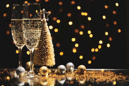 Champagne glasses and baubles against blurred lights background, space for textの写真素材