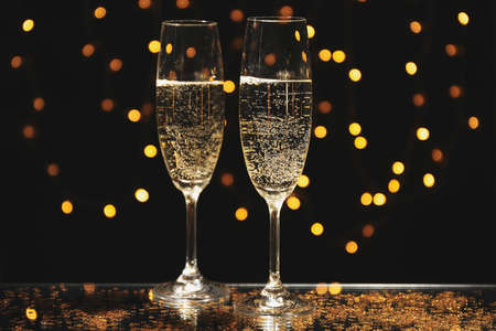 Champagne glasses against blurred lights background, space for text