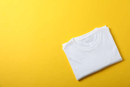 Folded blank white t-shirt on yellow background, space for textの写真素材