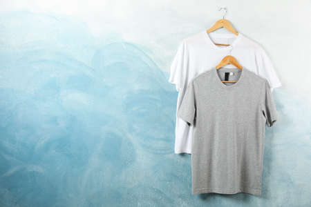 Hangers with blank white and gray t-shirts on blue background, copy spaceの写真素材