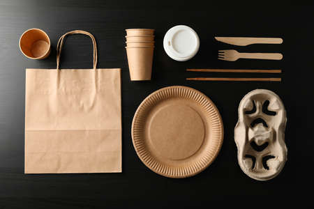 Flat lay with eco - friendly tableware on black background, top view