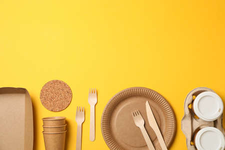 Flat lay with eco - friendly tableware on yellow background, space for text