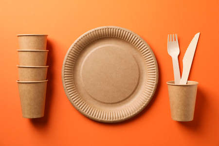 Flat lay with eco - friendly tableware on orange background, space for text