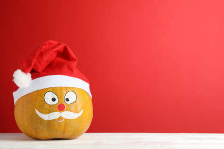 Pumpkin with mustache and red Santa hat against red background, copy spaceの写真素材