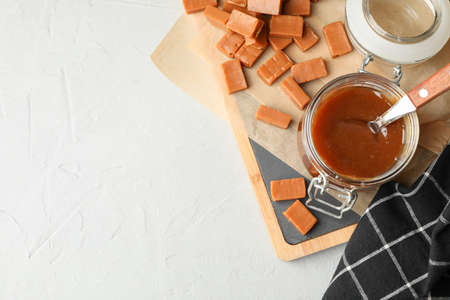 Glass jar with salted caramel and candies on grey background, copy spaceの写真素材