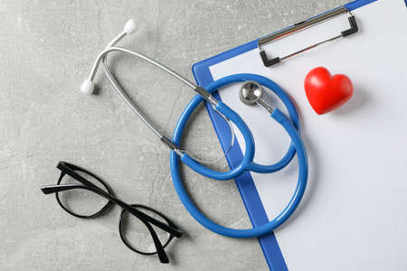 Stethoscope, heart, tablet and glasses on grey background, close upの写真素材