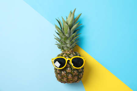 Pineapple with sunglasses on three tone background, space for text