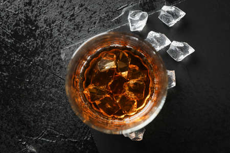 Glass of whiskey with ice cubes on black background, top viewの写真素材