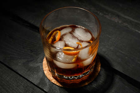 Glass of whiskey with ice cubes on dark wooden background, space for textの写真素材