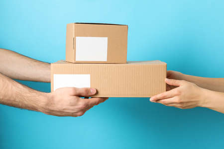 Woman receiving boxes from delivery man against blue background, blank spaceの写真素材