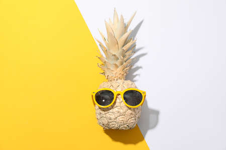 Painted gold pineapple with sunglasses on two tone background, space for textの写真素材
