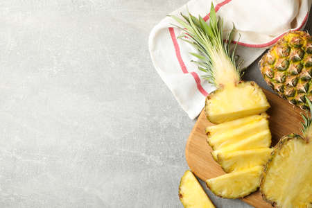 Cutting board with pineapples on grey background, top view