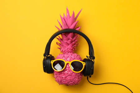 Painted pineapple with headphones and sunglasses on yellow background, space for textの写真素材