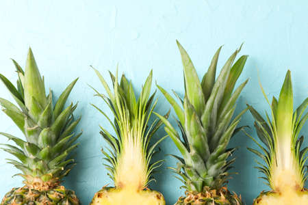 Top of pineapples on blue background, close up. Juicy fruit