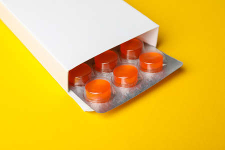 Blank pill box on yellow background, close upの写真素材