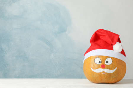 Pumpkin with mustache and red Santa hat against blue background, copy spaceの写真素材