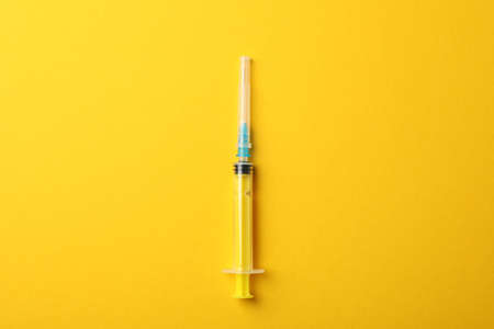 Syringe on yellow background, space for textの写真素材