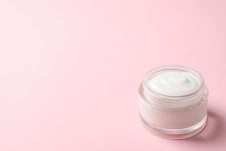 Jar of winter cream for skin on pink background, space for text
