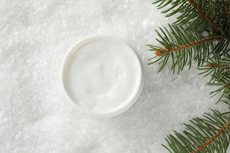 Jar of winter cream for skin, christmas tree on snowy background, space for text. Top view