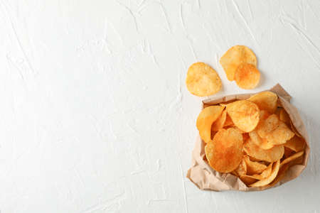 Paper bag of potato chips on white wooden background, space for text. Top viewの写真素材
