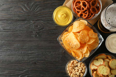 Beer snacks, glass of beer, potato chips, beer nuts, sauces, glass of beer on wooden background, space for text. Top viewの写真素材