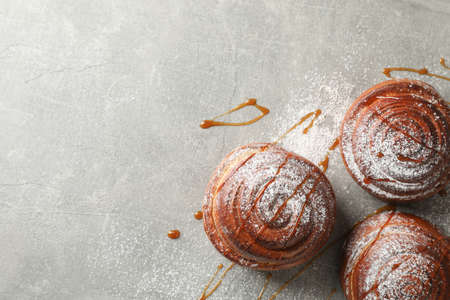 Cinnamon rolls with caramel and powdered sugar on grey background, top viewの写真素材
