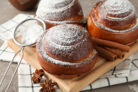 Tasty cinnamon roll with ingredients, coffee on brown table against blue background, closeup. Top...