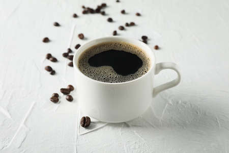 Cup of coffee and beans on white background, close up