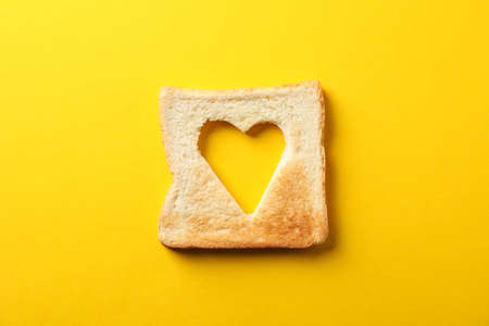 Toast bread with shape of heart on yellow background, top viewの写真素材
