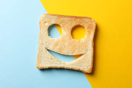 Bread toast with happy face on two tone background, top view