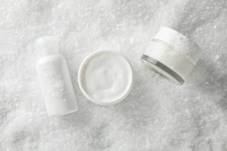 Set cosmetics, jar of winter cream for skin on snowy background, space for text. Top view