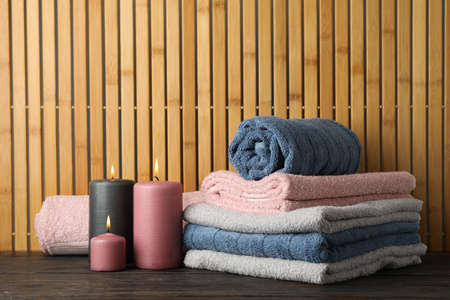 Towels and candles on wooden table against bamboo background, space for textの写真素材